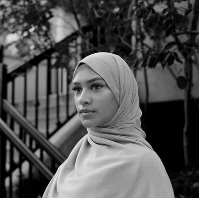 a woman in a hijab standing in front of a stair case