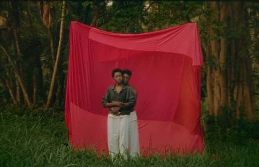 a man standing in front of a red sheet