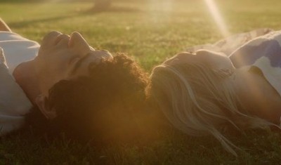 a woman laying in the grass with her head on her back