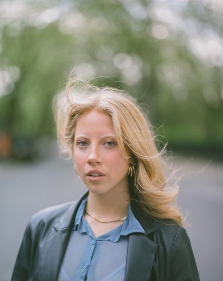 a woman in a blue shirt and black jacket