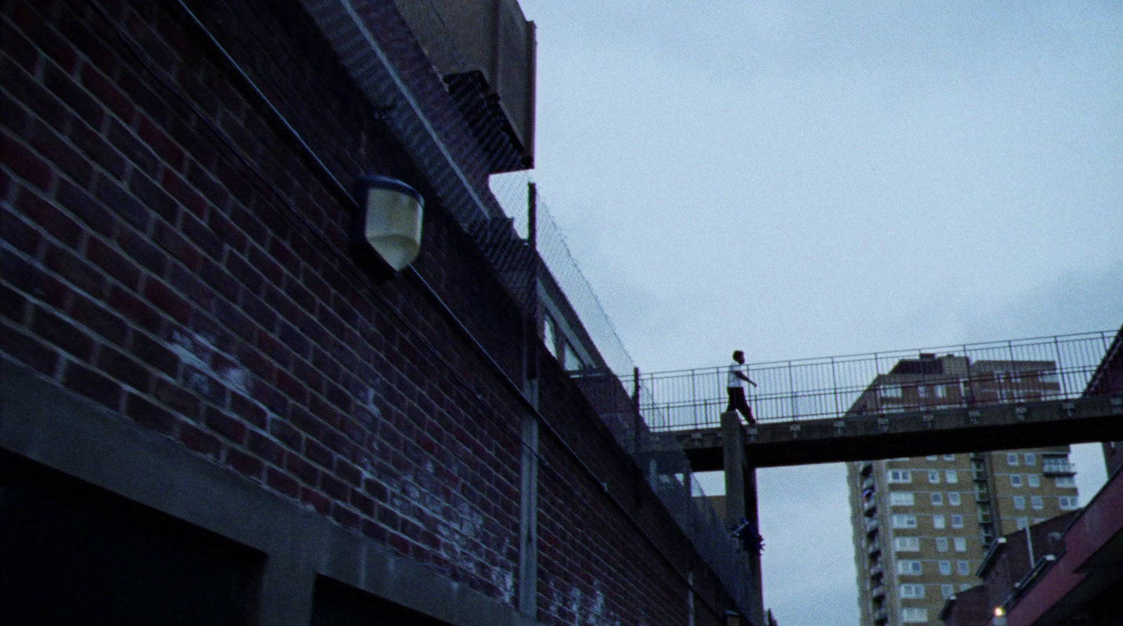 a man walking across a bridge over a street