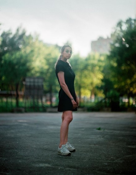 a woman in a black dress standing in a parking lot