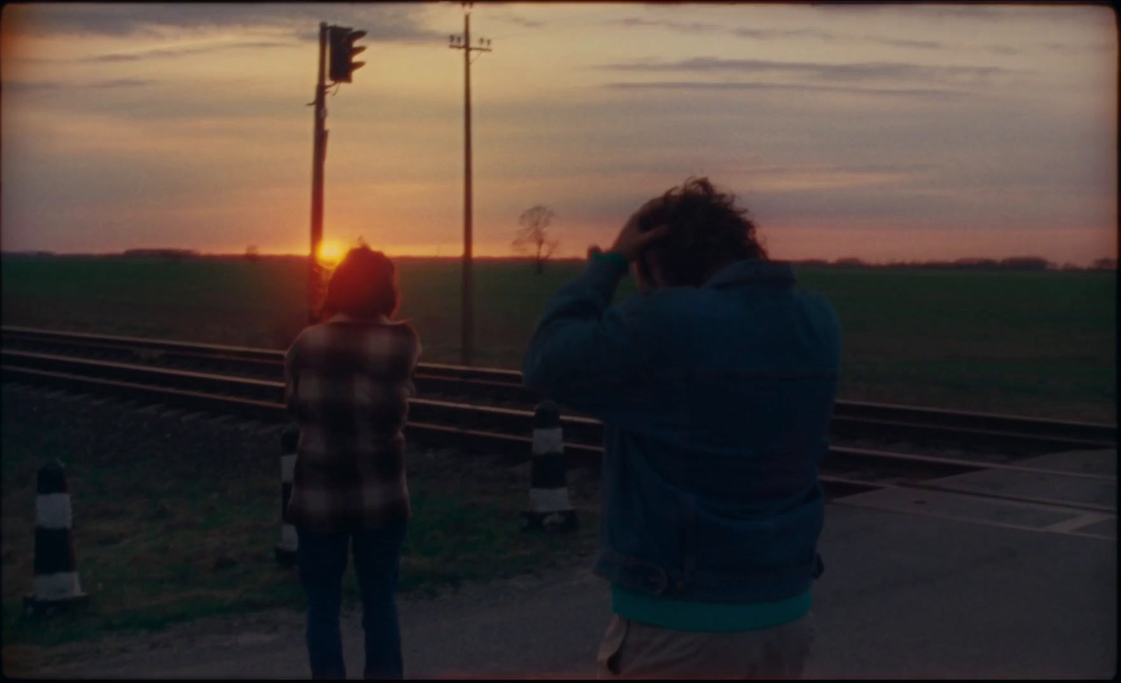 a couple of people standing next to a train track