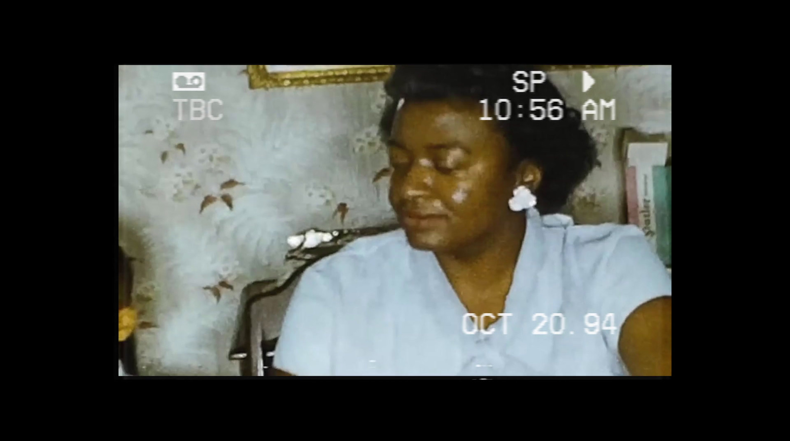 a woman sitting in front of a wall with a clock on it