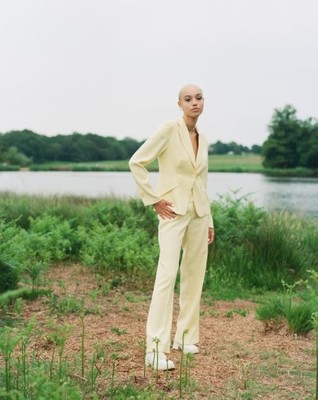 a woman standing in a field next to a body of water