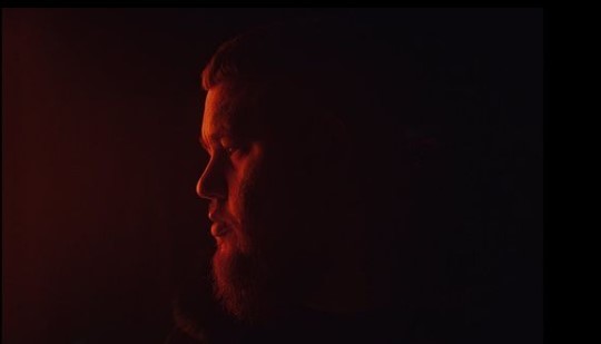 a man with a beard standing in the dark