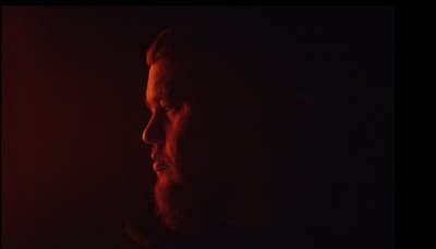 a man with a beard standing in the dark