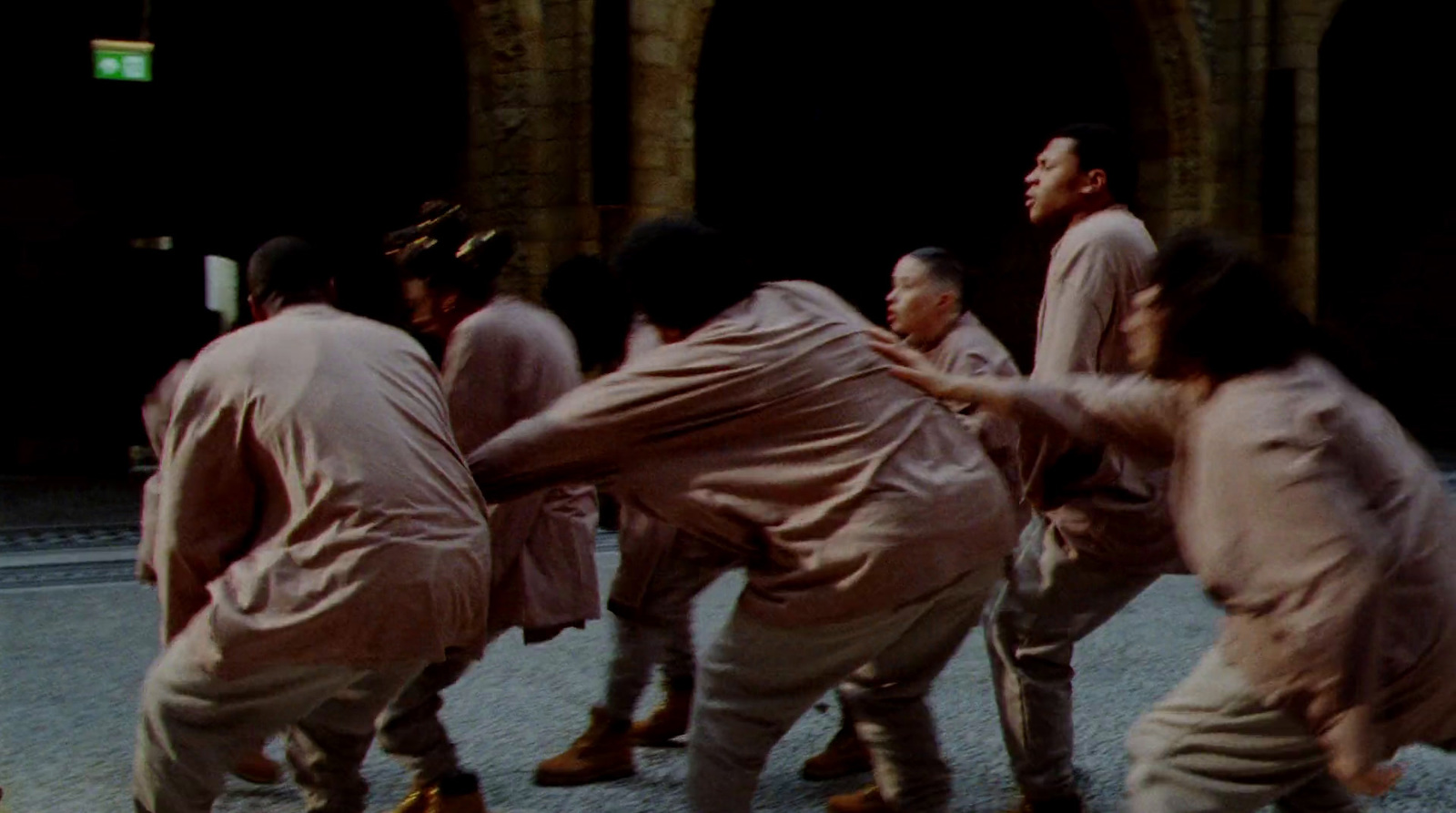 a group of men in khaki dancing in front of a building