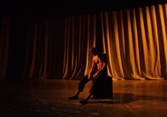 a man sitting on a chair in front of a curtain