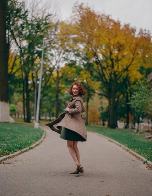 a woman walking down a sidewalk in a park