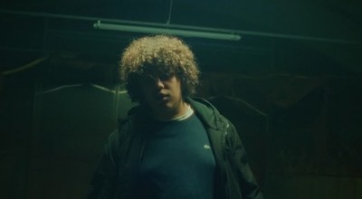 a man with curly hair standing in a dark room