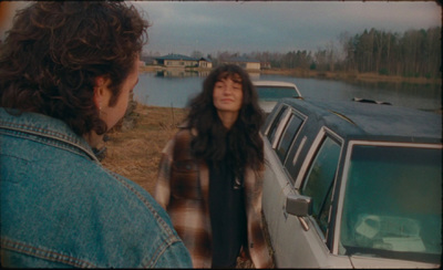 a woman standing next to a car near a body of water