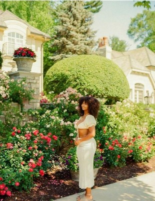 a woman standing on a sidewalk in front of a house