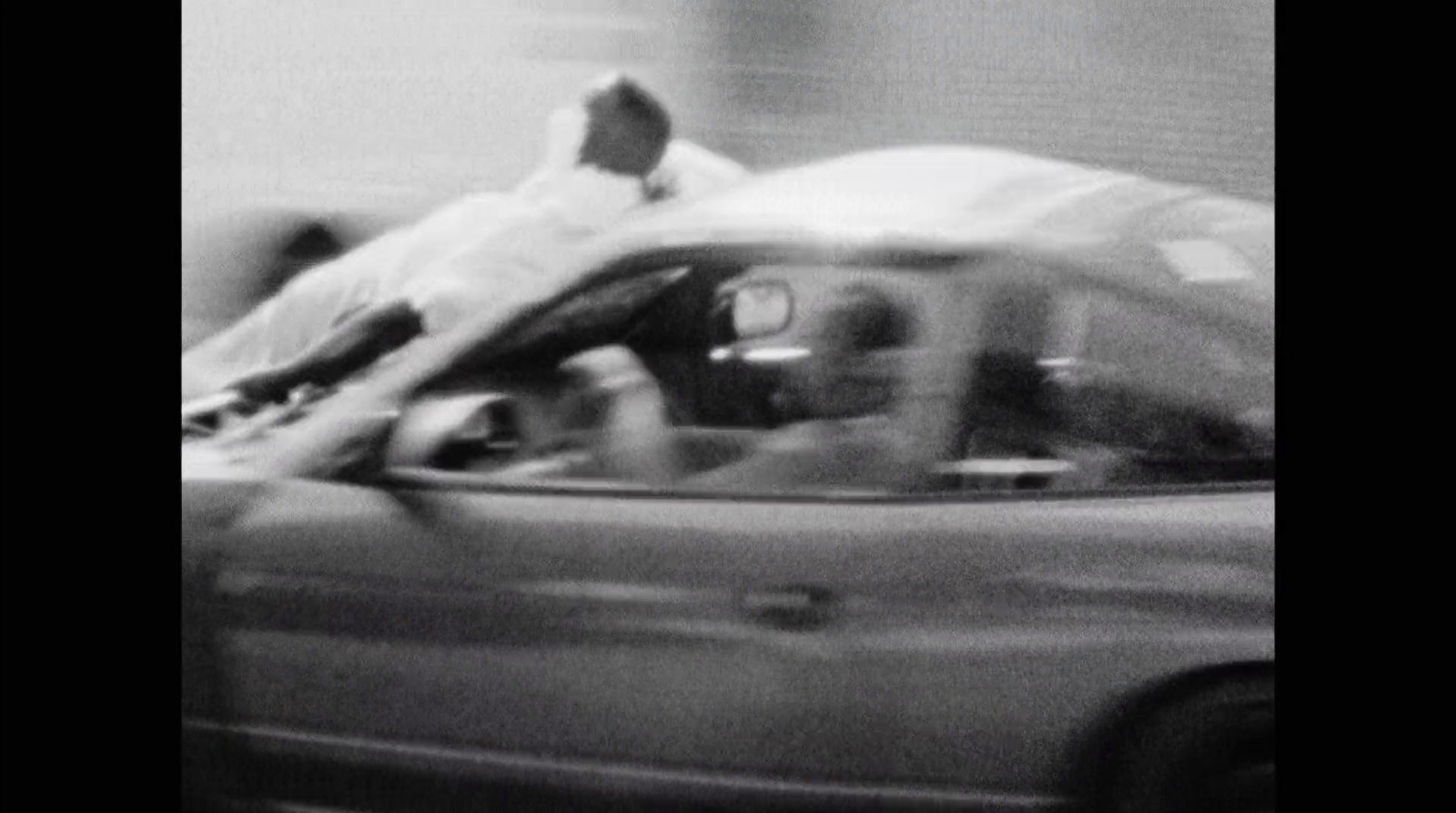 a blurry photo of a man laying on top of a car