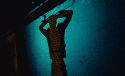 a person standing in the dark with their hands on their head