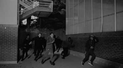 a group of people walking down a sidewalk next to a building