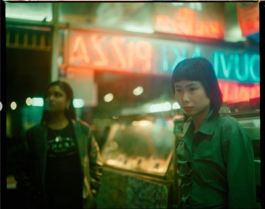 a woman standing next to a man in front of a pizza shop