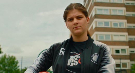 a woman holding a football in front of a tall building