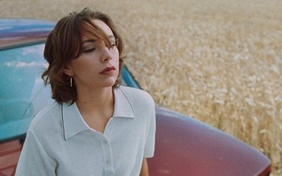 a woman standing next to a car in a field