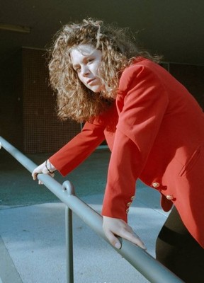 a woman in a red jacket leaning on a railing