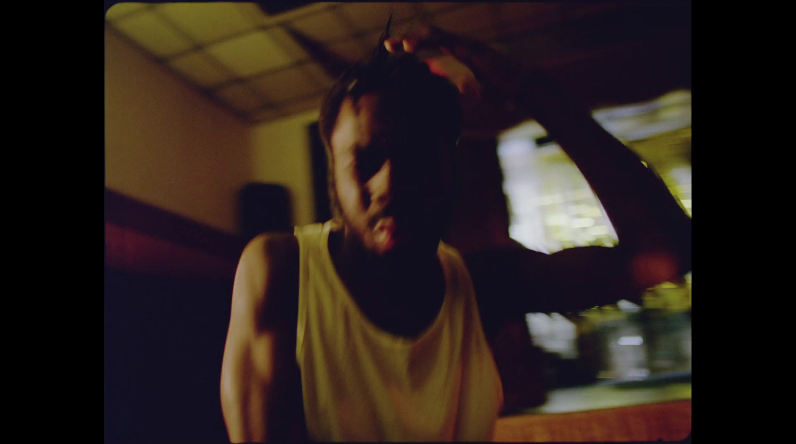 a man in a tank top brushing his hair