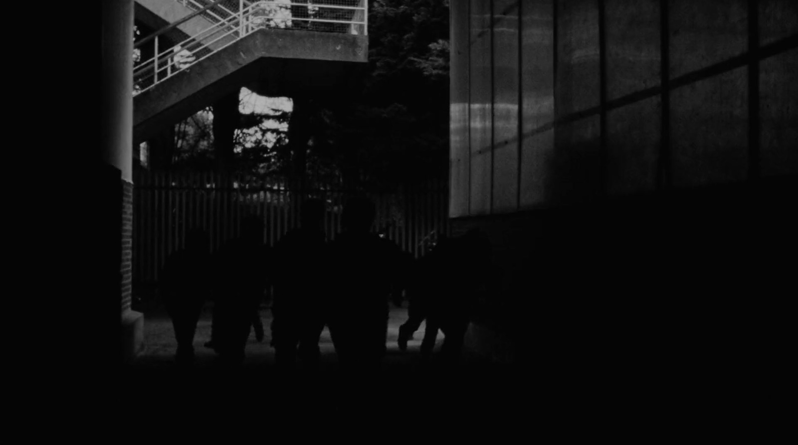 a black and white photo of people walking under a bridge