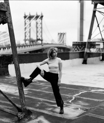 a black and white photo of a woman leaning against a pole