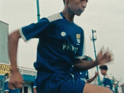 a young man running with a soccer ball in his hand