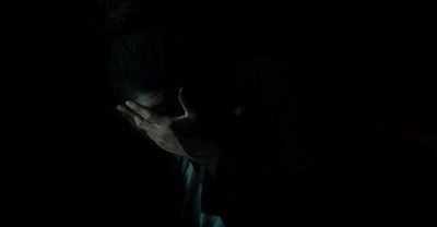 a man in the dark covering his face with his hands