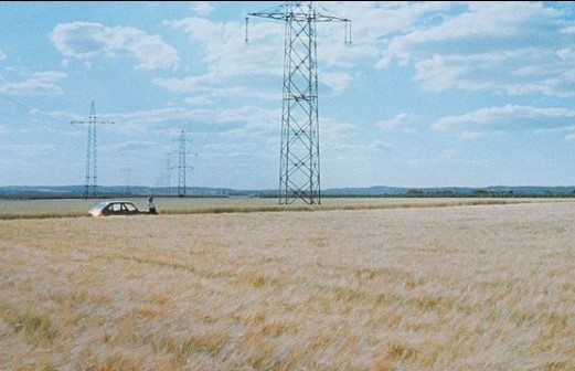 a car is parked in a field with power lines in the background