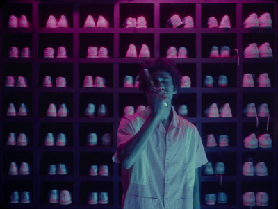 a man standing in front of a wall of shoes