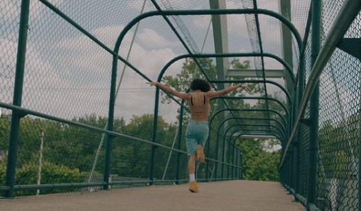 a man running across a bridge with his arms outstretched