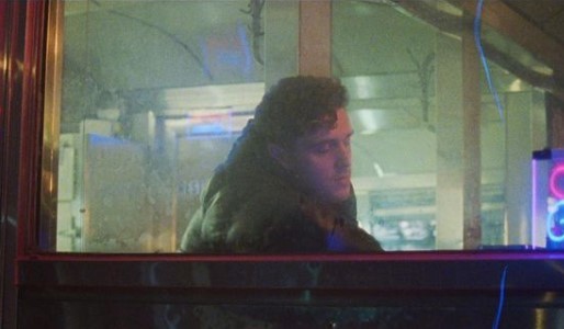 a man sitting at a table in front of a neon sign