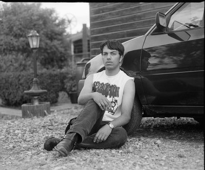 a man sitting on the ground next to a car