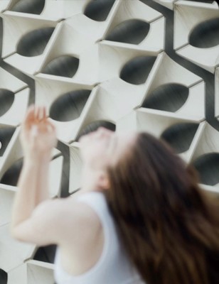 a woman standing in front of a wall with a clock on it