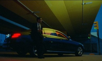 a man standing next to a car under a bridge