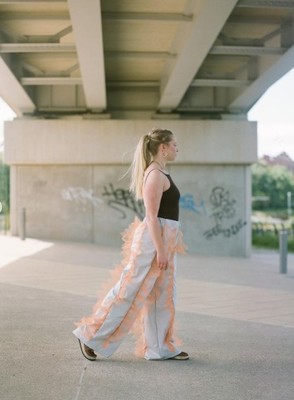 a woman in a long dress walking under a bridge