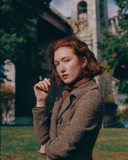 a woman standing in front of a building with a clock tower in the background