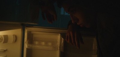 a man looking into an open refrigerator in the dark