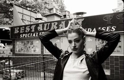 a black and white photo of a woman standing in front of a restaurant