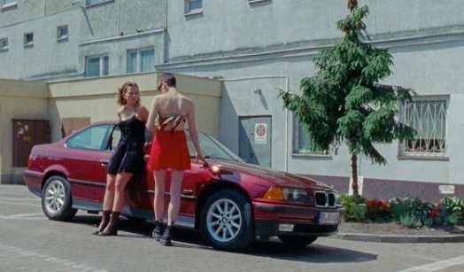 a couple of women standing next to a red car