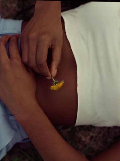 a woman in a white shirt holding a yellow flower