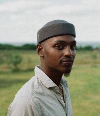 a man standing in a field wearing a hat