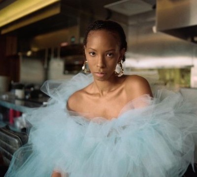 a woman in a blue dress standing in a kitchen