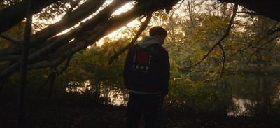 a man standing under a tree next to a body of water