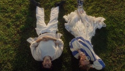 a couple of people laying on top of a lush green field