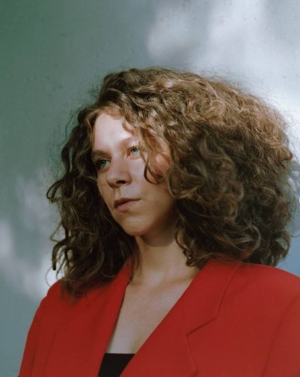 a woman with curly hair wearing a red jacket