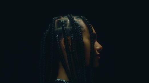 a woman with long braids standing in the dark