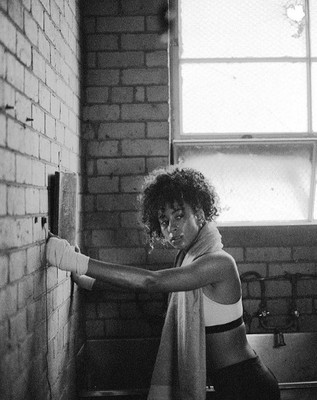 a black and white photo of a woman leaning against a brick wall