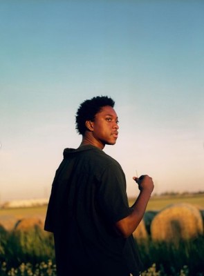 a man standing in a field with hay bales in the background